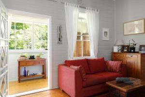 Una sala de estar con un sofá rojo y una ventana. en Blue Mountains Bliss Cottages Katoomba - Rosebud, en Katoomba
