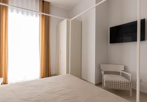 a bedroom with a bed and a tv and a chair at Palazzo Albergamo in Favara