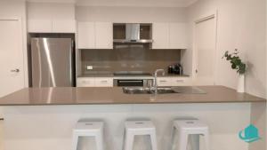 eine Küche mit Spüle und Theke mit Hockern in der Unterkunft The Sanctuary at Catherine Hill Bay in Catherine Hill Bay