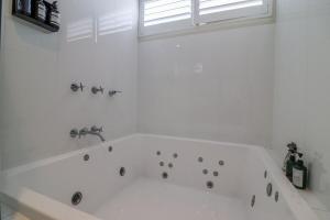 uma banheira branca na casa de banho com uma janela em Haven at Caves em Caves Beach