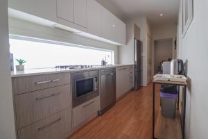 a kitchen with stainless steel appliances and a large window at Haven at Caves in Caves Beach