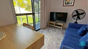 sala de estar con sofá azul y TV en Casuarina Waters - waterfront home on Lake Macquarie, en Bonnells Bay