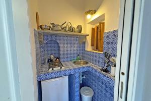 uma cozinha em azulejos azuis com um lavatório e um balcão em Casa Corallo em Panarea