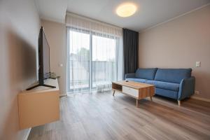 a living room with a blue couch and a tv at Windway Apartments in Otepää