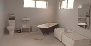 a bathroom with a tub and a toilet and a sink at Betty's Bay Cottage in Bettyʼs Bay +63 photos