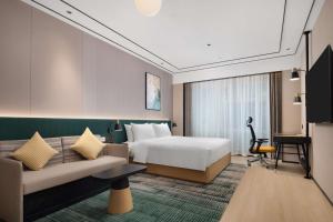 une chambre d'hôtel avec un lit et un canapé dans l'établissement Hilton Garden Inn Chengdu Chunxi Road Center, à Chengdu