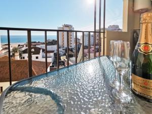 une table en verre avec une bouteille et des verres sur un balcon dans l'établissement Apartment Praia Rocha Vista Mar Sand, à Portimão