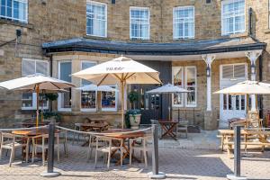 a group of tables and umbrellas in front of a building at Rooms by Bistrot Pierre at The Crescent Inn in Ilkley