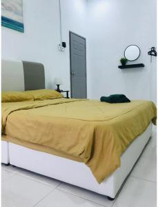 a bed with a yellow blanket on it in a bedroom at De Lumpur Guest House in Kuantan