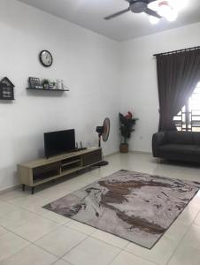 a living room with a tv and a couch and a table at De Lumpur Guest House in Kuantan +3 photos
