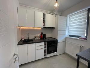 eine Küche mit weißen Schränken, einer Spüle und einem Fenster in der Unterkunft Metropolis Elegance in Bukarest