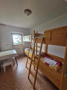 Zimmer mit 2 Etagenbetten und einem Tisch in der Unterkunft Črnuški dom na Mali planini in Krivčevo
