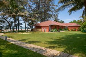 a house with a green yard and palm trees at Mandrem Beach Resort, a member of Radisson Individuals Retreat in Mandrem
