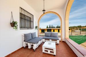 a patio with a couch and a table and a window at Casa rural Montemayor in Moguer