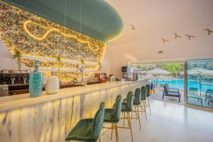 a bar with green chairs and a swimming pool at Zoe Hotel, Trypiti Beach Resort & Hive water park in Limenaria