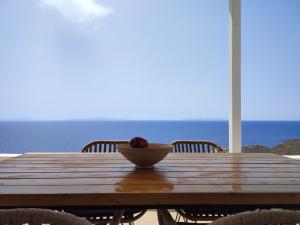 un bol de fruta sentado en una mesa de madera con el océano en Sifnos "Sofia apartments" sea view, en Faros