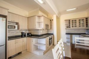 - une cuisine avec des placards en bois et des appareils blancs dans l'établissement Saints View Resort Unit 20, à Uvongo Beach