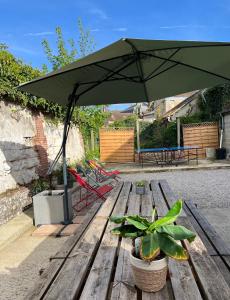 uma mesa de piquenique com um guarda-chuva verde e um banco em Maison 6 chambres em Beauvais