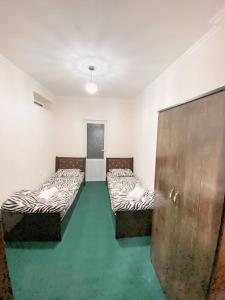 três camas num quarto com pisos verdes e uma porta em Registan Family Hotel em Samarkand