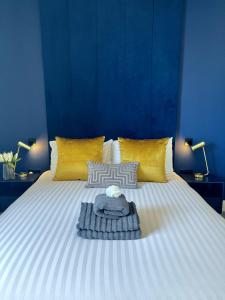 a large white bed with yellow pillows and a blue wall at Luxury Norwich City Centre Apartment - Free Parking in Norwich