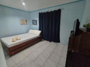 een kleine slaapkamer met een bed en een televisie bij RedDoorz @ Raj Inn Guimaras in Oracon