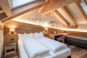 ein Schlafzimmer mit einem weißen Bett an einer Holzwand in der Unterkunft Hotel Bellavista in Cavalese