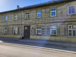un antiguo edificio de madera al lado de una calle en Old Town Family Apartment, en Valga