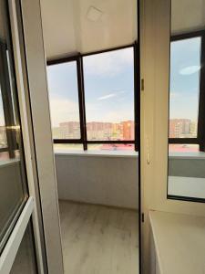 um quarto vazio com janelas e vista para a cidade em 1-комнатная комфортная кухня-студия со всеми удобствами em Qostanay