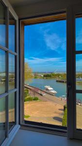 a window with a view of a body of water at Best Western Le Cheval Blanc -Vue sur le port-plein centre ville in Honfleur