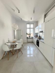 een grote witte keuken met een tafel en stoelen bij Słoneczny Apartament w Centrum in Słupsk