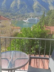 a balcony with a table and a cruise ship in the water at Bay View Apartments in Kotor
