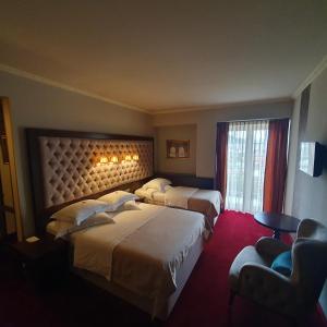 una habitación de hotel con 2 camas y una silla en Simfonia Boutique Hotel, en Râmnicu Vâlcea
