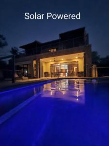 uma piscina em frente a uma casa à noite em Rosendal Kruger View Villa em Marloth Park