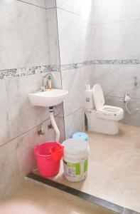 a bathroom with a sink and a toilet and buckets at Hotel Hari Krishnashrya in Vrindāvan