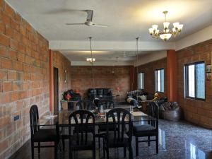 a dining room with a table and chairs and a brick wall at Spacious farmhouse in Vikārābād