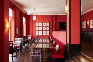 ein Restaurant mit roten Wänden, Tischen und Stühlen in der Unterkunft Strandhotel Zingst in Zingst