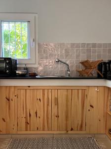 cocina con armarios de madera, fregadero y ventana en Appartement 2 chambres avec Jardin privé sur la côte Nord, en Calodyne