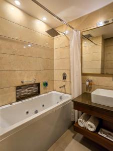 a bathroom with a bath tub and a sink at Grand View Hotel in Dalhousie