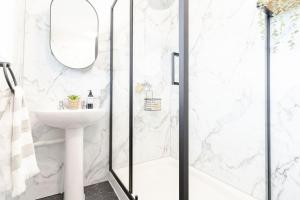 Un baño blanco con ducha y lavabo. en Rosandric, en Bude 23 fotos más