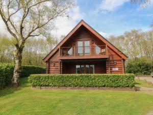 a log house with a balcony and a tree at Willow in Winkleigh