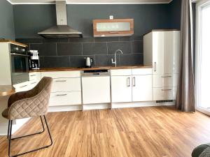 a kitchen with white cabinets and a sink and a chair at DAS AMBIENTE II Komfortables Wohnerlebnis mit Moselromantik - Herzlich Willkommen - in Zell an der Mosel +23 photos