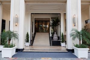 una entrada a un edificio con escaleras y palmeras en Hotel Maharaja Palazzo en Ludhiana