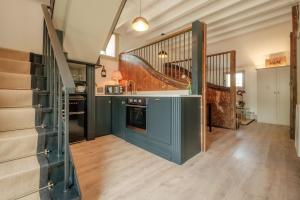 a large kitchen with blue cabinets and a staircase at The Old Stables in Newcastle upon Tyne