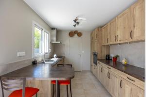 a kitchen with wooden cabinets and a counter with red chairs at La petite maison de Littry in Le Molay-Littry