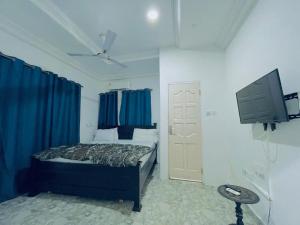 1 dormitorio con 1 cama con cortinas azules y TV en Nana's Holiday Let, en Accra