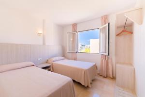 una camera d'albergo con due letti e una finestra di Apartamentos Avenida - MC Apartamentos Ibiza a Ibiza Città