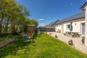 a group of benches in the grass next to a building at La petite maison de Littry in Le Molay-Littry