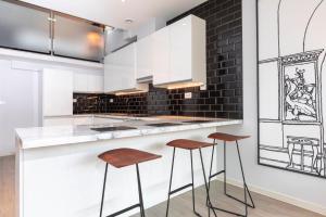 a kitchen with white counters and brown stools at Palm Tree House - Angles Max in Orpington