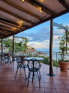 un patio con mesas y sillas y vistas al océano en Villa Pino en Furore