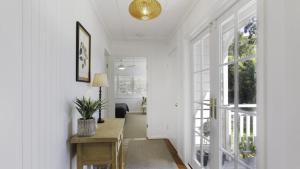 einen Flur mit weißen Wänden und einem Tisch mit Pflanze in der Unterkunft 'Wagstaffe Cottage' by HolidayCo in Booker Bay